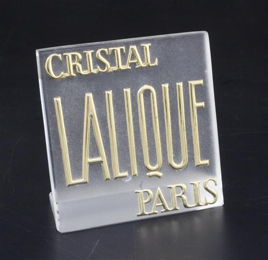 A Lalique frosted glass Crystal Lalique display label with raised gilt lettering, 10 x 10cm.